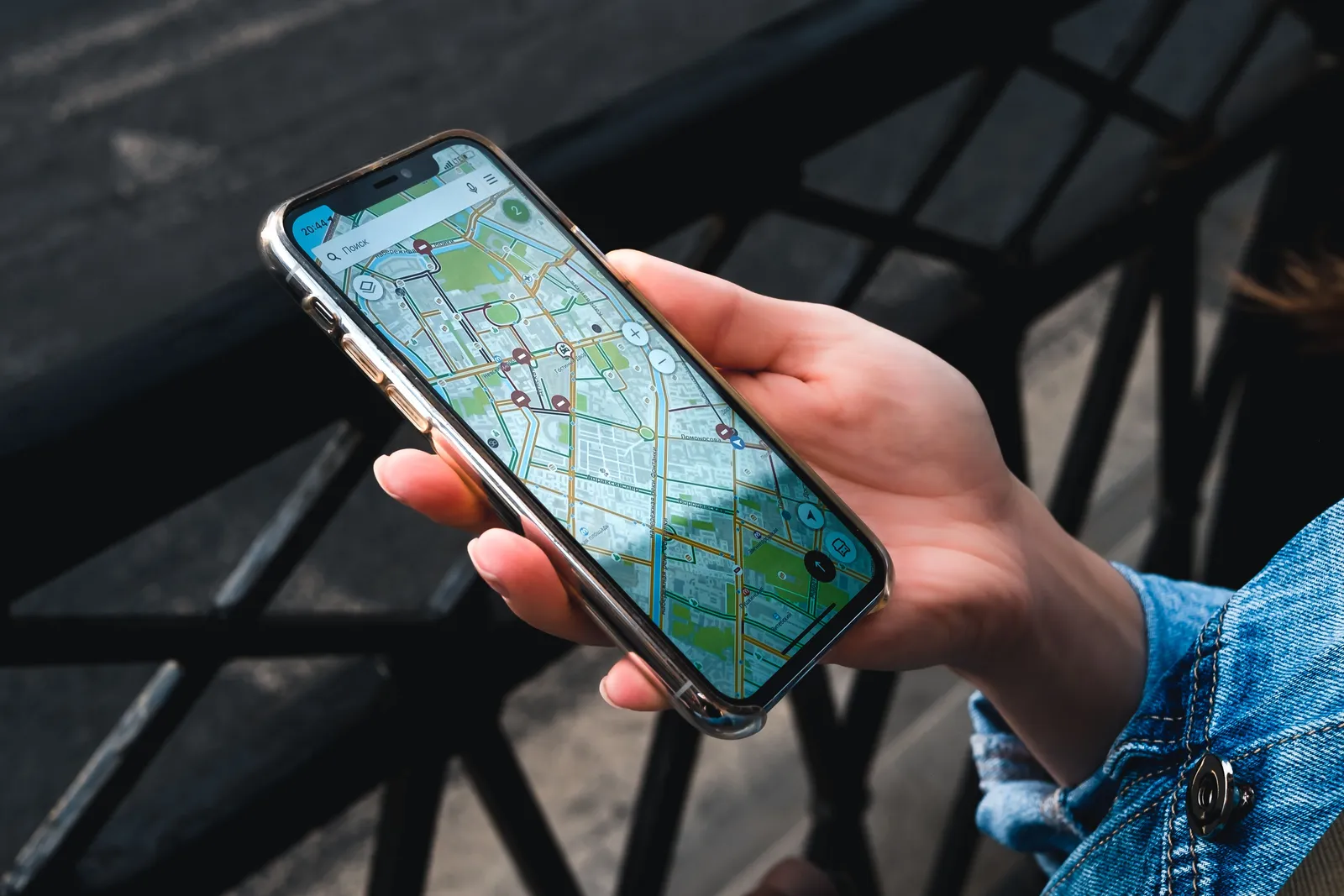 Mano sosteniendo un móvil con un mapa de la ciudad abierto en la calle