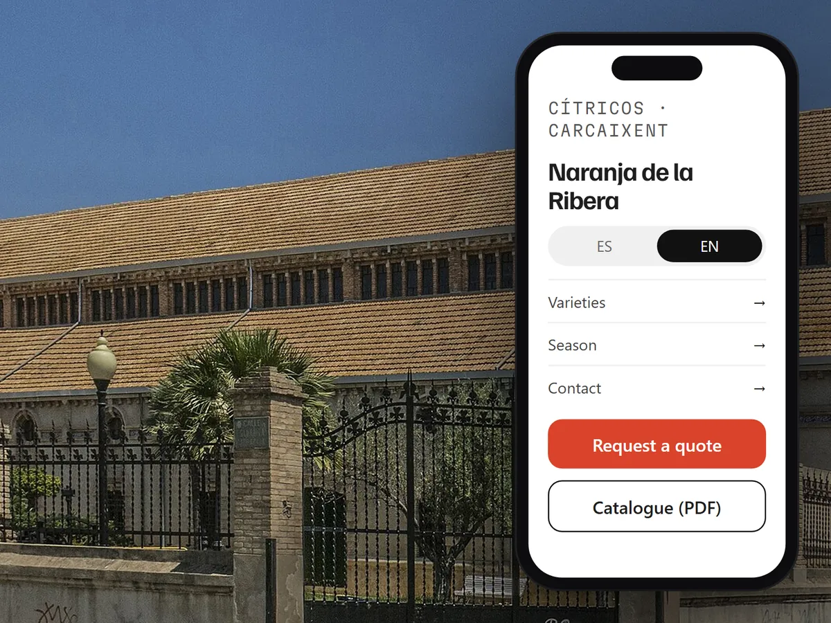 Fachada del antiguo almacén de naranja Magatzem de Ribera en Carcaixent y la web de una empresa de cítricos en el móvil
