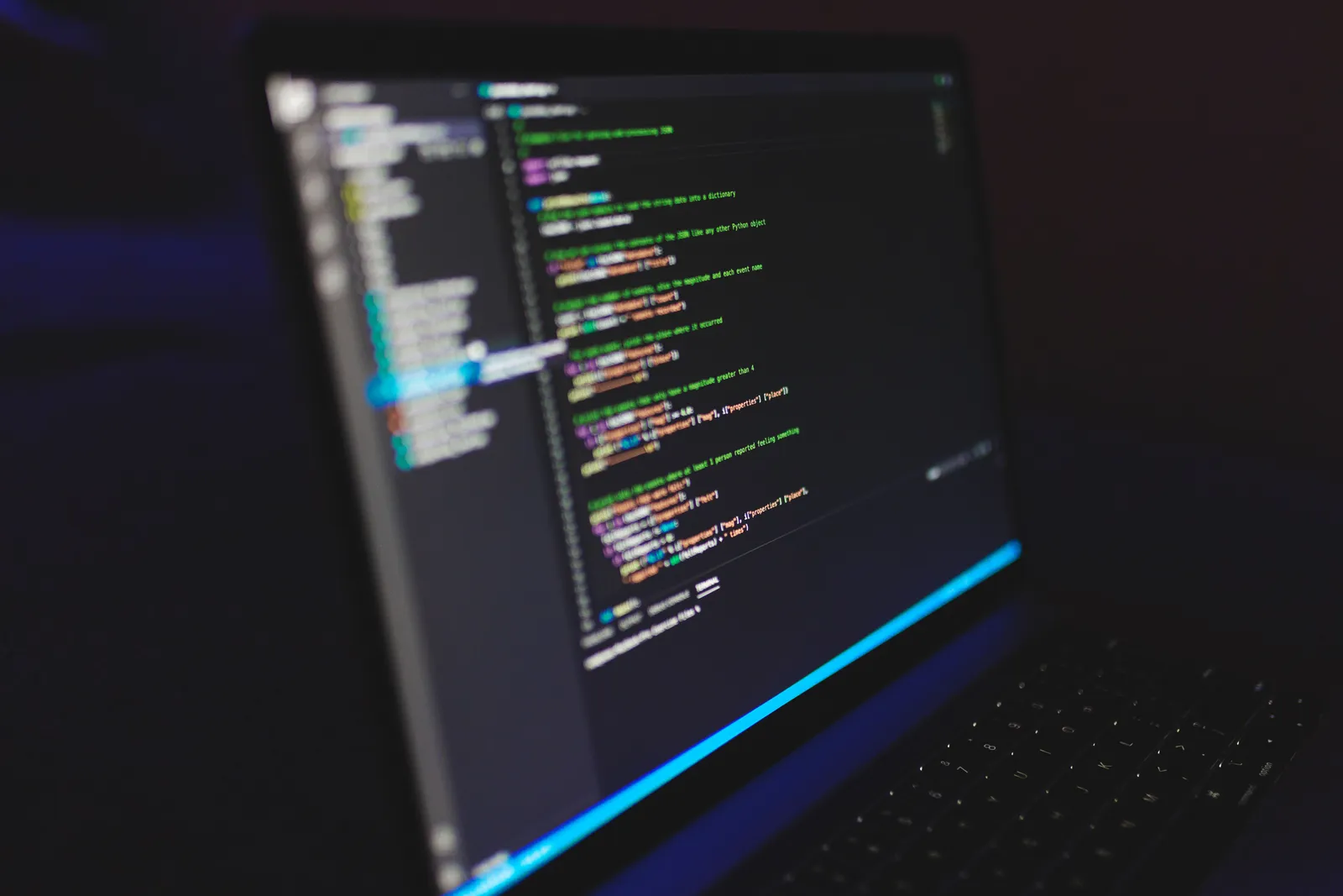Portátil con código de una página web en pantalla, en un escritorio en penumbra